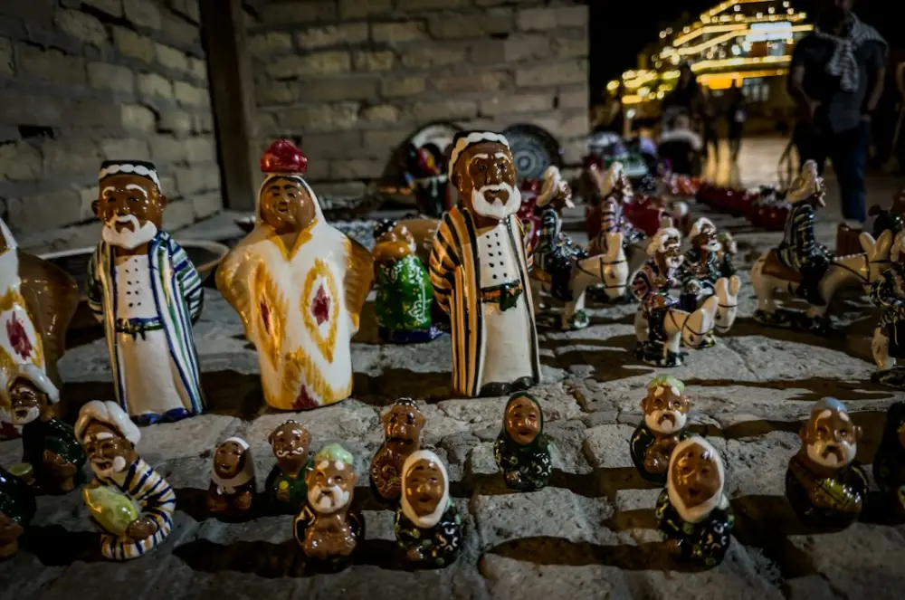 Handcrafted ceramic figurines of people in traditional clothing on a stone street at night, illustrating narrative craft